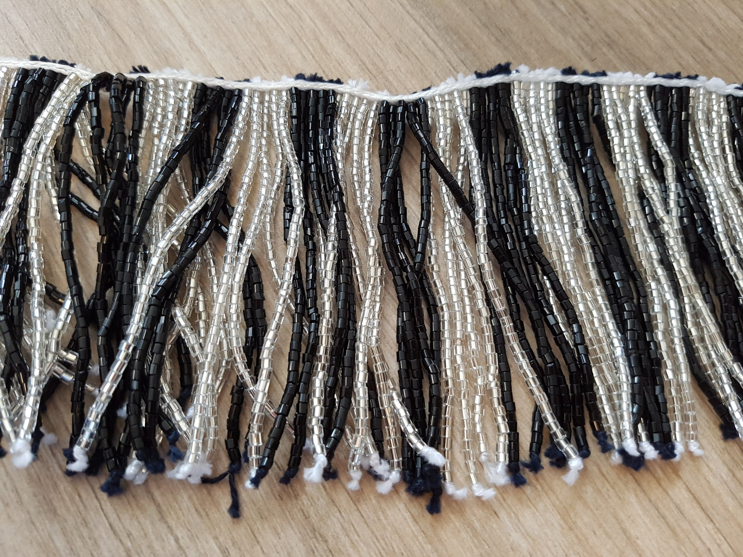 Perlenkette mit schwarz/weißen Schnüren und vielen Perlen

 60cm lang, Stränge 20cm lang